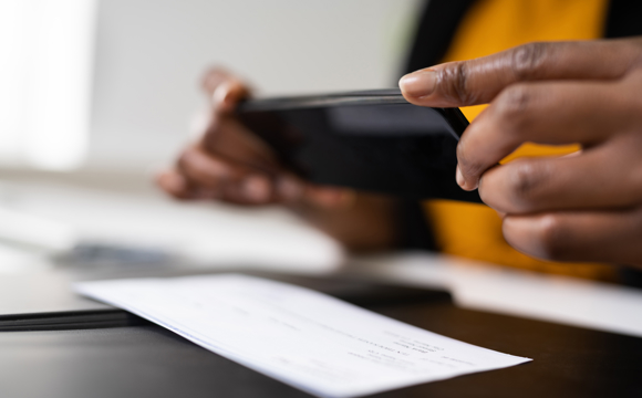 A closeup of a phone taking a photo of a check.