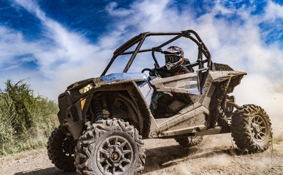 Driving a muddy ATV through the dirt.