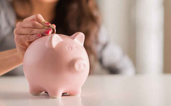 A women putting money into her piggy bank.