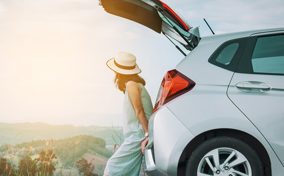 A women sitting on the edge of the trunk of her SUV.