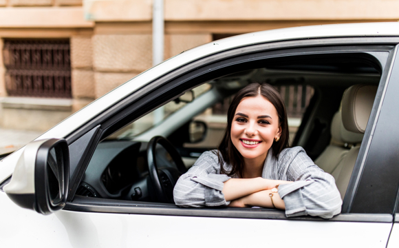 A woman leaning out the driver window of her car.