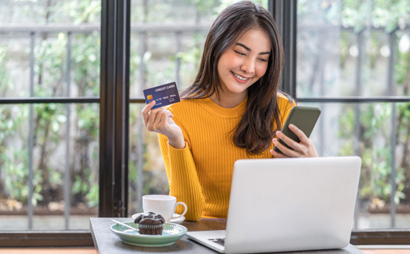 A teenager holding her debit card while online shopping.