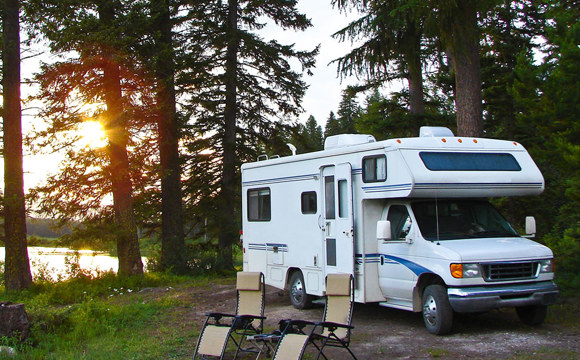 A RV parked in a forest campground.