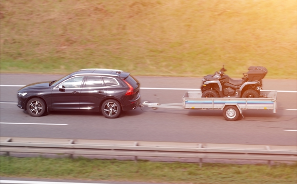 A SUV pulling a small utility trailer.