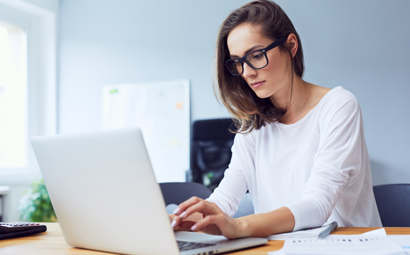 A women writing a report on her laptop.