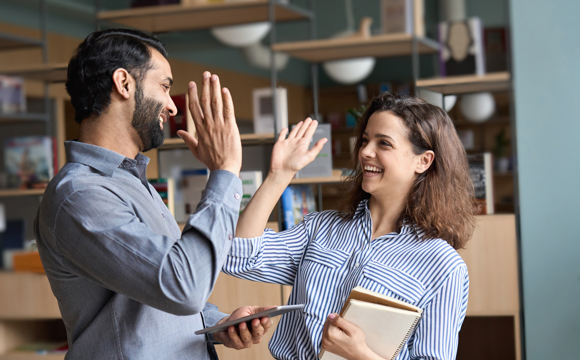 A man and woman high-fiving each other inside their modern new business.