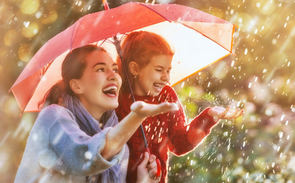A mom holding an umbrella for both her and her daughter in the rain.