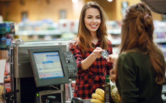 A women handing a grocer her debit card.