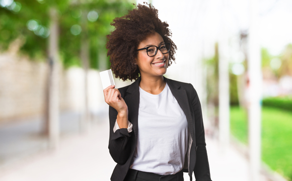 A woman in a blazer holding up her debit card.